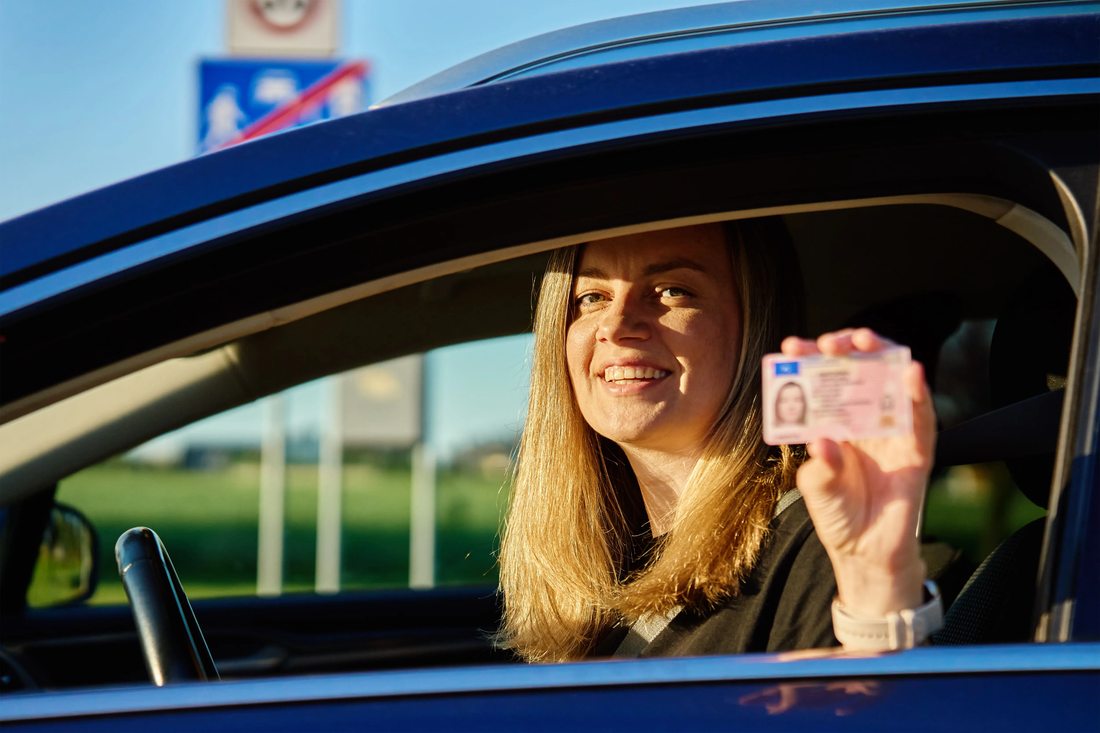 Glückliche Fahrschülerin zeigt ihren neuen Führerschein