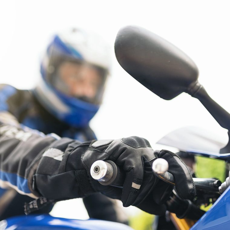 Motorradfahrer mit Helm und Handschuhen am Lenker